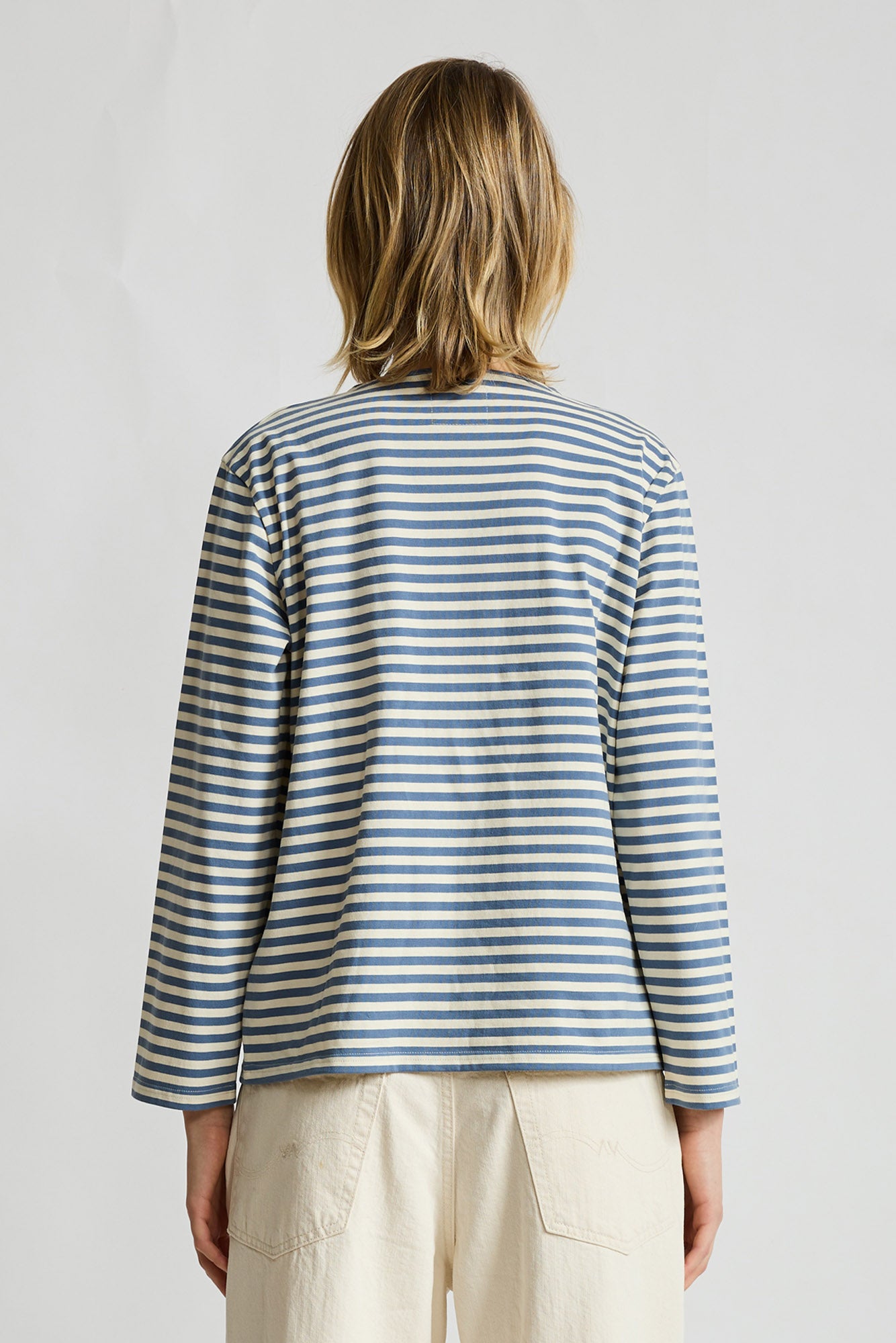 Long-sleeve striped tee with blue and cream horizontal stripes, shown from back view on model.